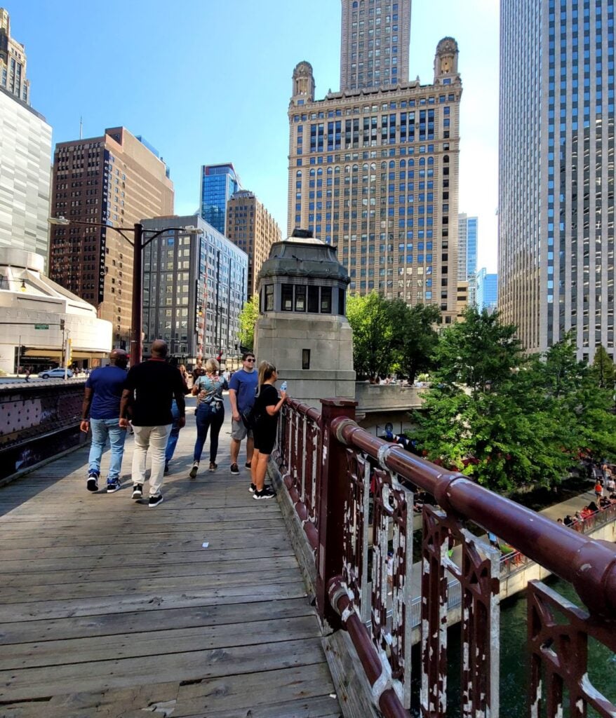People walking along the Chicago Riverwalk with downtown skyline views