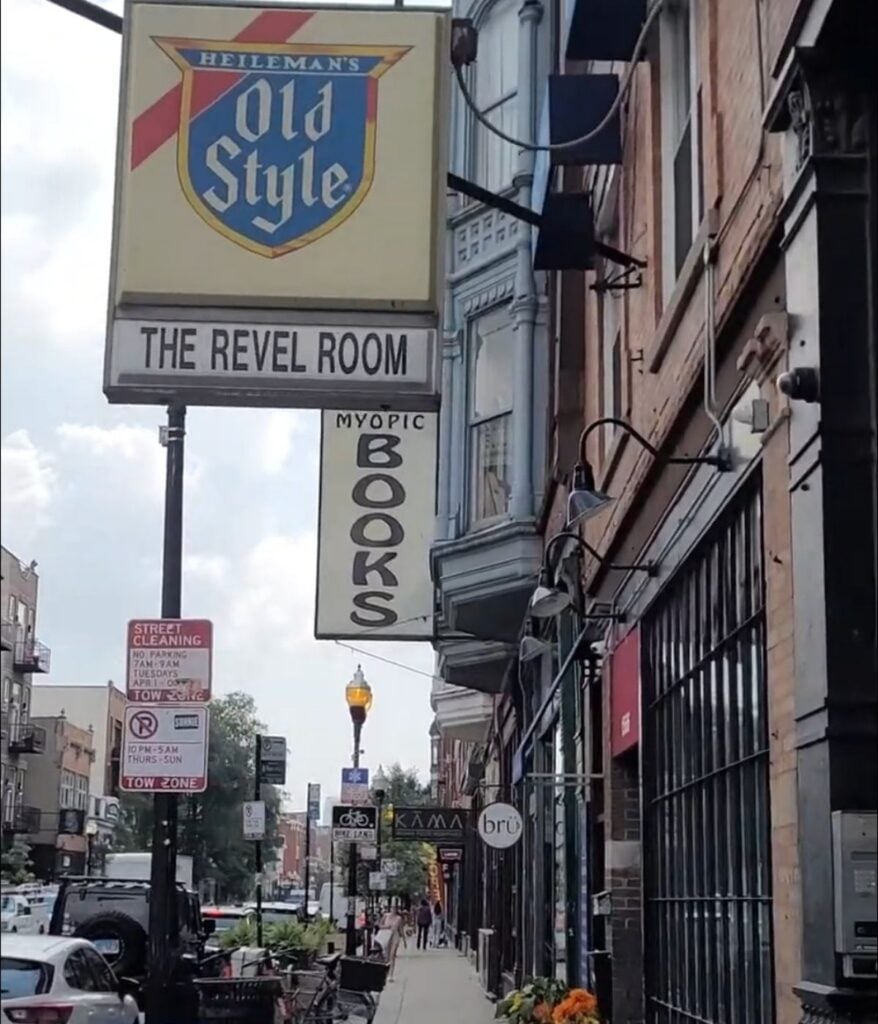 Street view in Wicker Park Chicago with The Revel Room sign and Myopic Books storefront along a neighborhood sidewalk