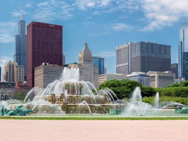 Buckingham Fountain spraying water in Grant Park with the Chicago skyline in the background on a sunny day.