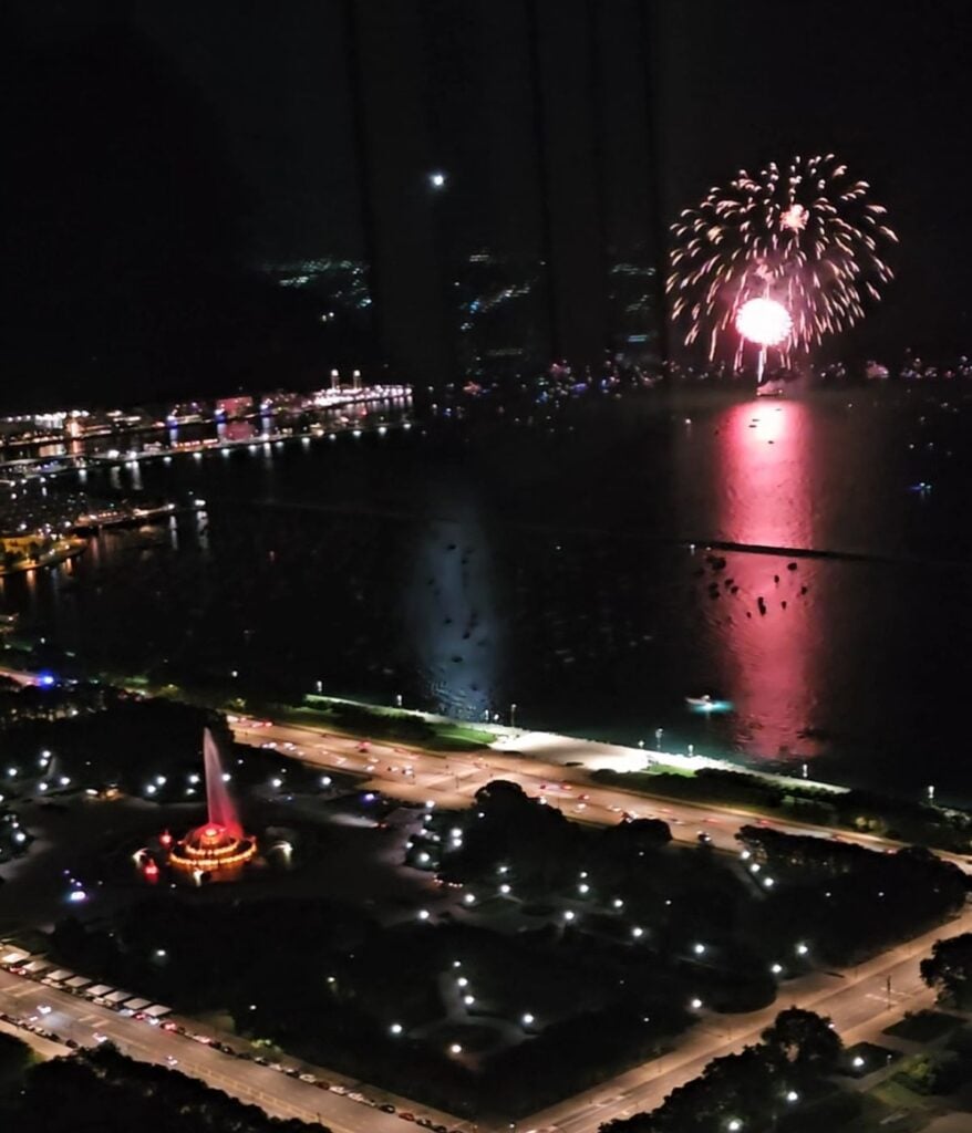 Fireworks exploding over Lake Michigan near Navy Pier and Buckingham Fountain during a summer night in Chicago.