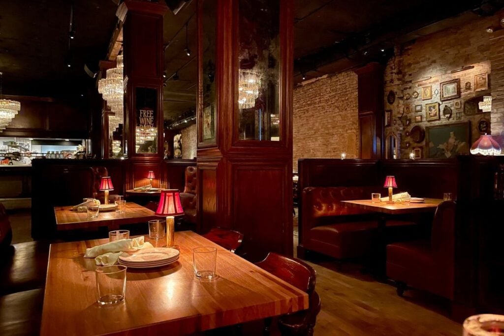Dim, candlelit dining room with red lamps and leather booths at Bavette's Bar & Boeuf in River North, Chicago