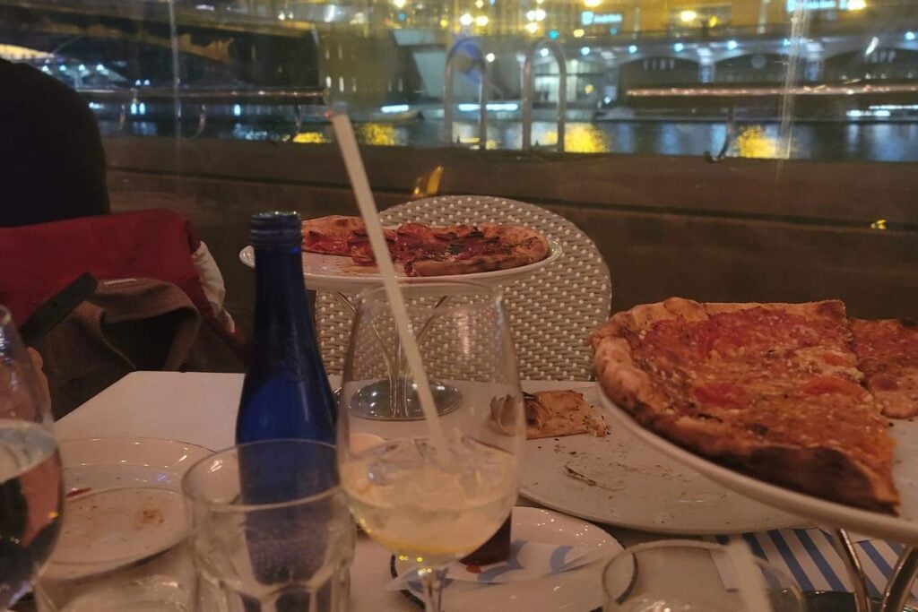Two pizzas on a table with the Chicago River visible through the window at Pizzeria Portofino