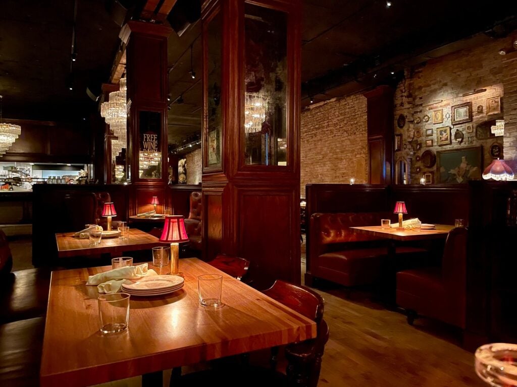 Dim, candlelit steakhouse dining room with red table lamps, leather booths, and exposed brick in Chicago