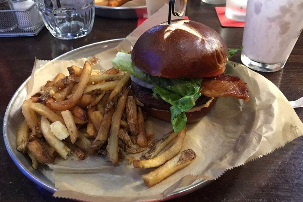 Burger on a pretzel bun with bacon, lettuce, and hand-cut fries at Burger Bar Chicago in the South Loop