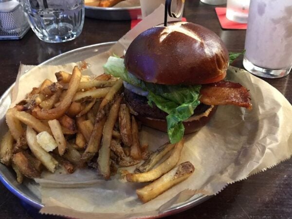 Burger on a pretzel bun with bacon, lettuce, and hand-cut fries at Burger Bar Chicago in the South Loop