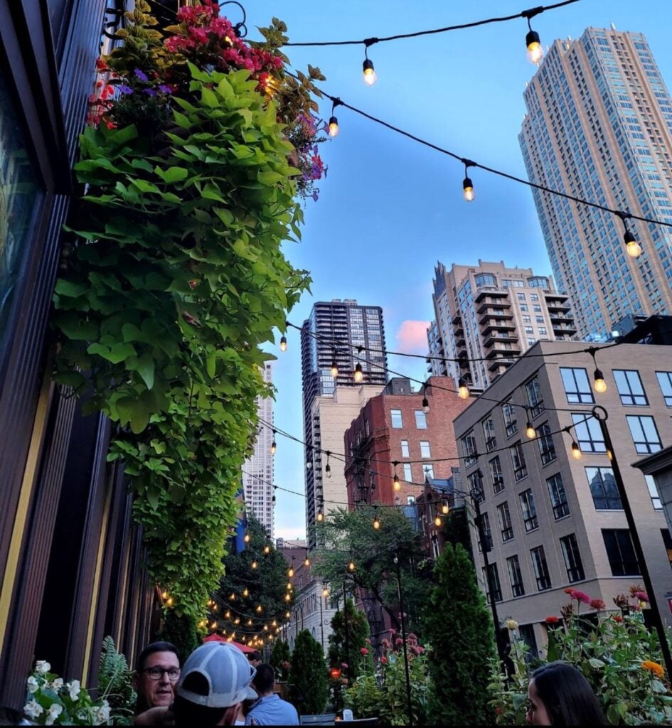 Outdoor patio dining in downtown Chicago at dusk with string lights and high-rise buildings