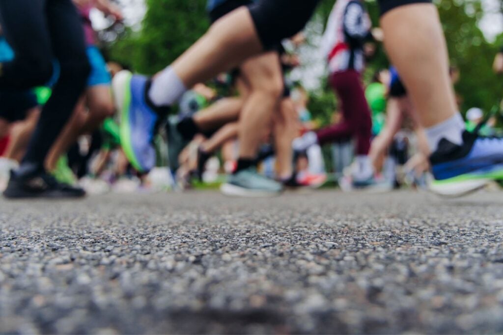 Close-up of runners' legs and shoes at the start of a road race on city pavement