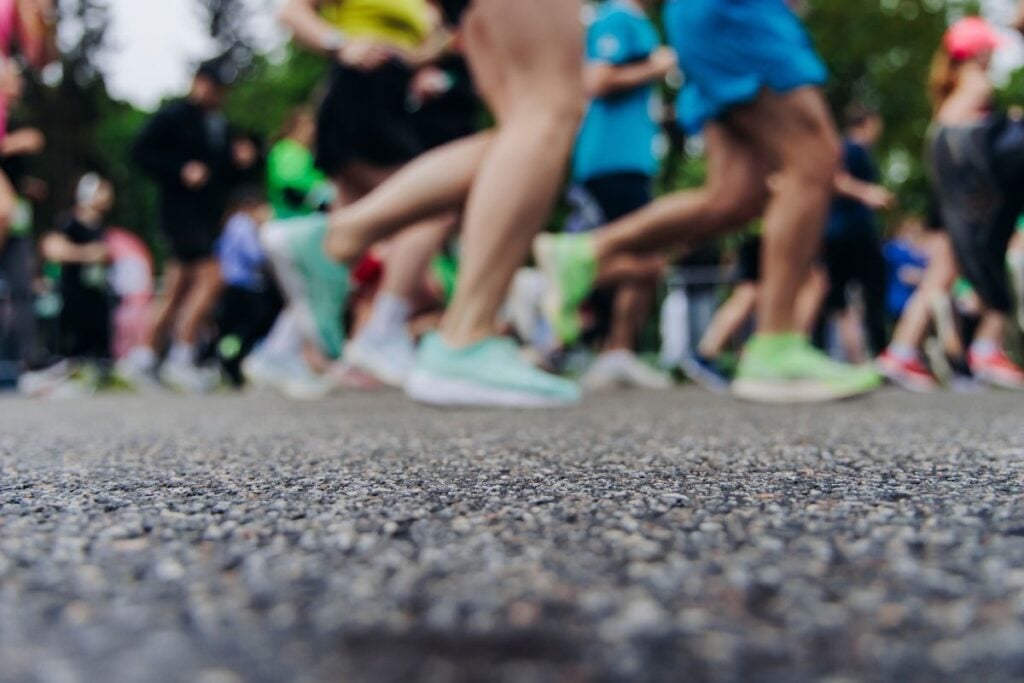Low-angle view of runners' legs and shoes mid-stride at the start of a road race
