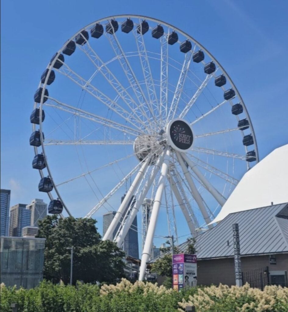 The Centennial Wheel at Navy Pier in Chicago against a clear blue summer sky, with the downtown skyline behind it