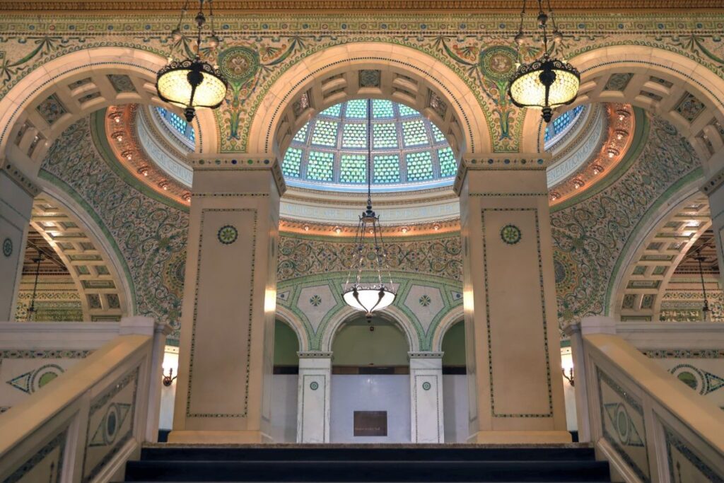 Intricate mosaic-tiled arches, light fixtures, and a glass dome interior at the Chicago Cultural Center
