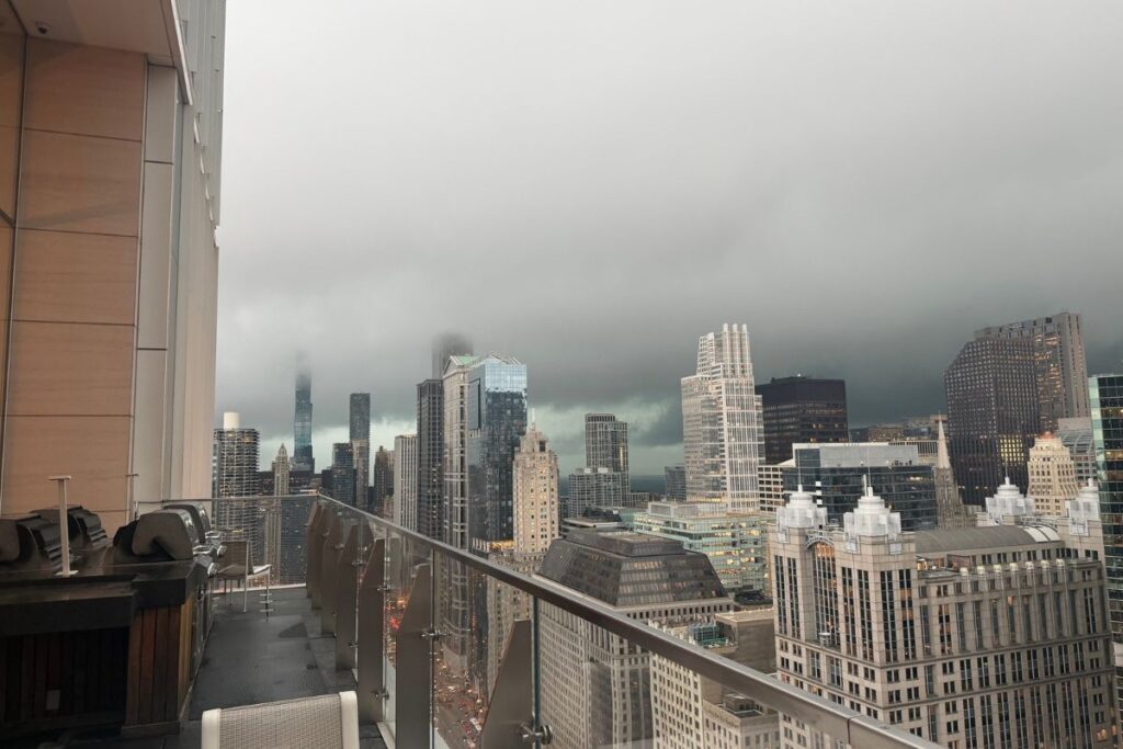 Overcast dark storm clouds and low fog rolling over downtown Chicago skyscrapers viewed from a high-rise balcony